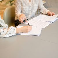 Close-up shot of two people working at a desk with paperwork.