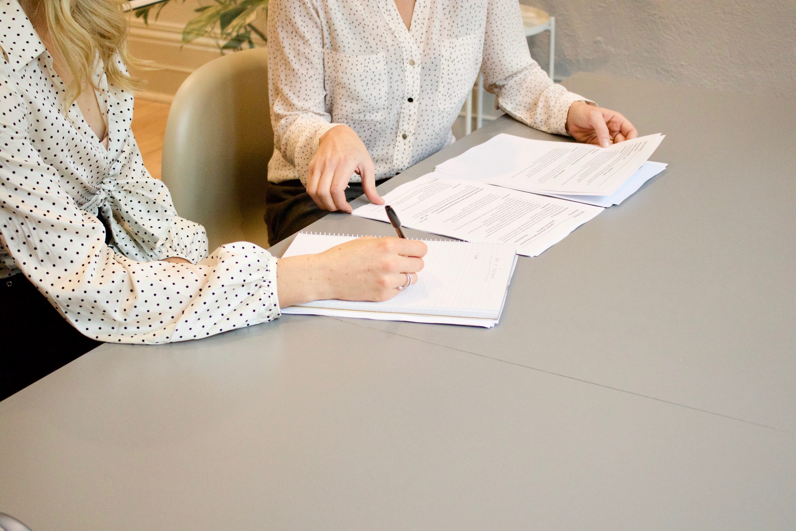 Close-up shot of two people working at a desk with paperwork.