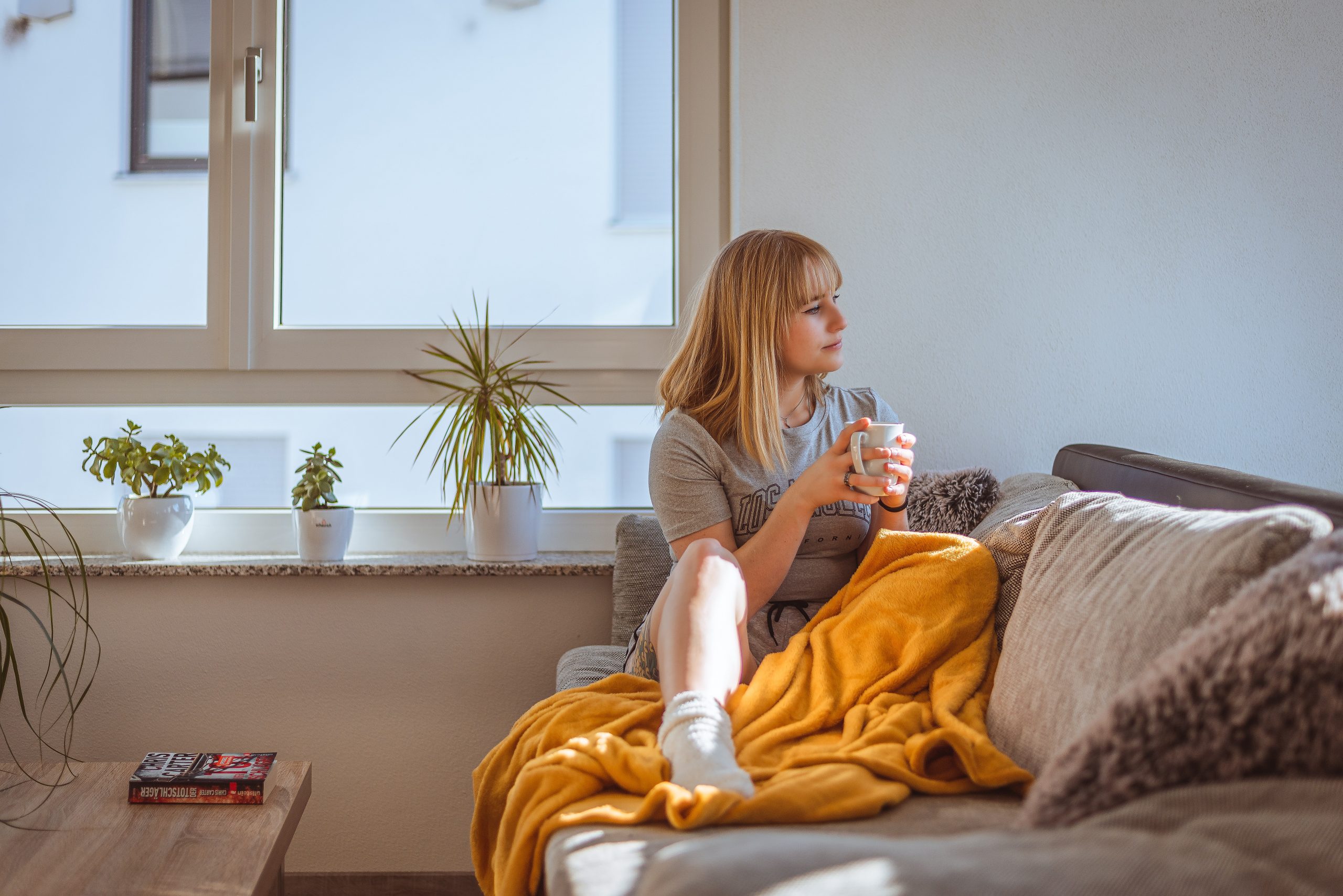 A woman sits in a loungeroom on a couch and thinks.