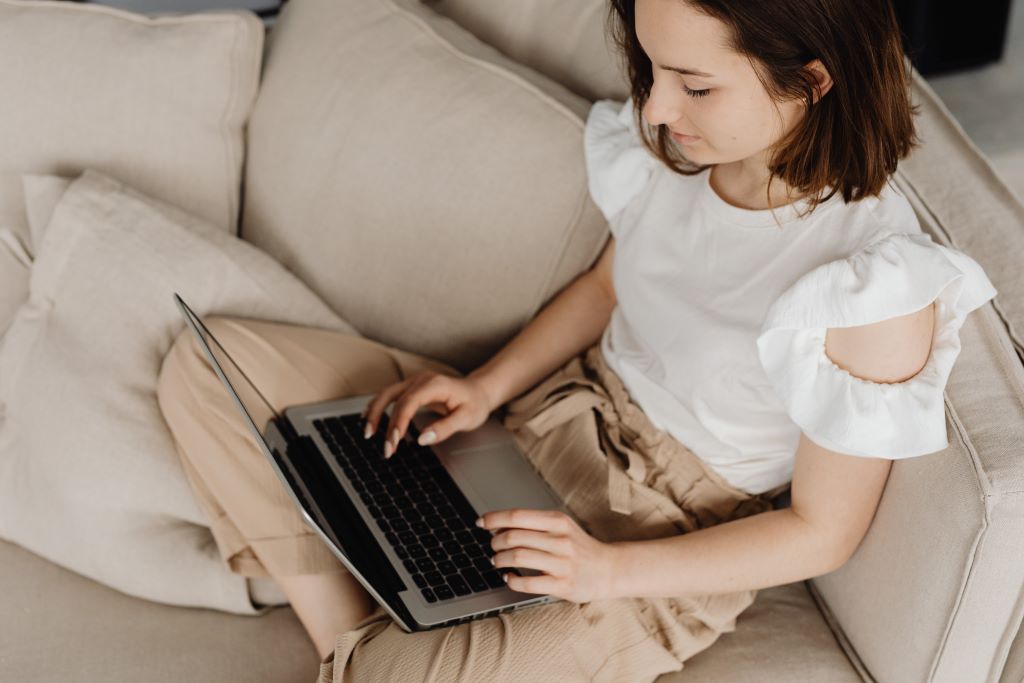 Woman working at her computer and sitting on the couch