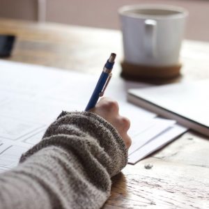 A close-up shot of a hand holding a pen filling out paperwork.