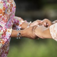 Two women hold hands and stand close to each other.