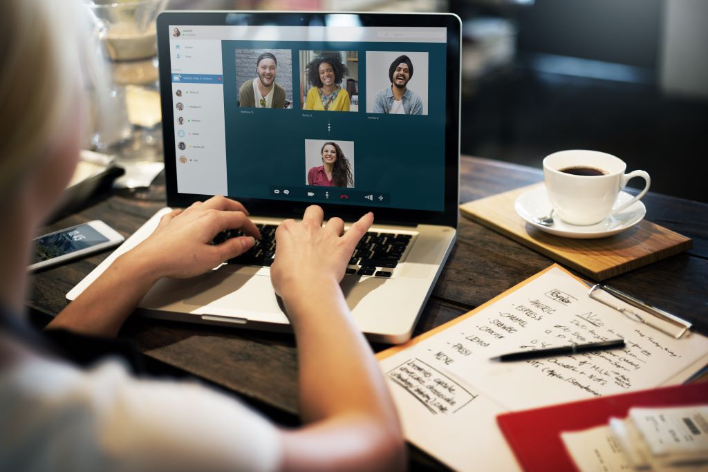 A woman sits at a computer and attends a zoom chat.