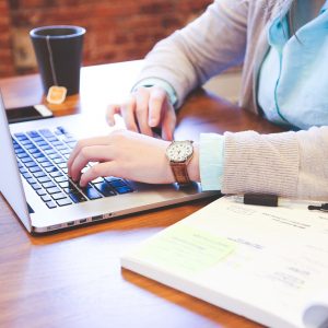 A close-up shot of a woman working at a desk on a computer.