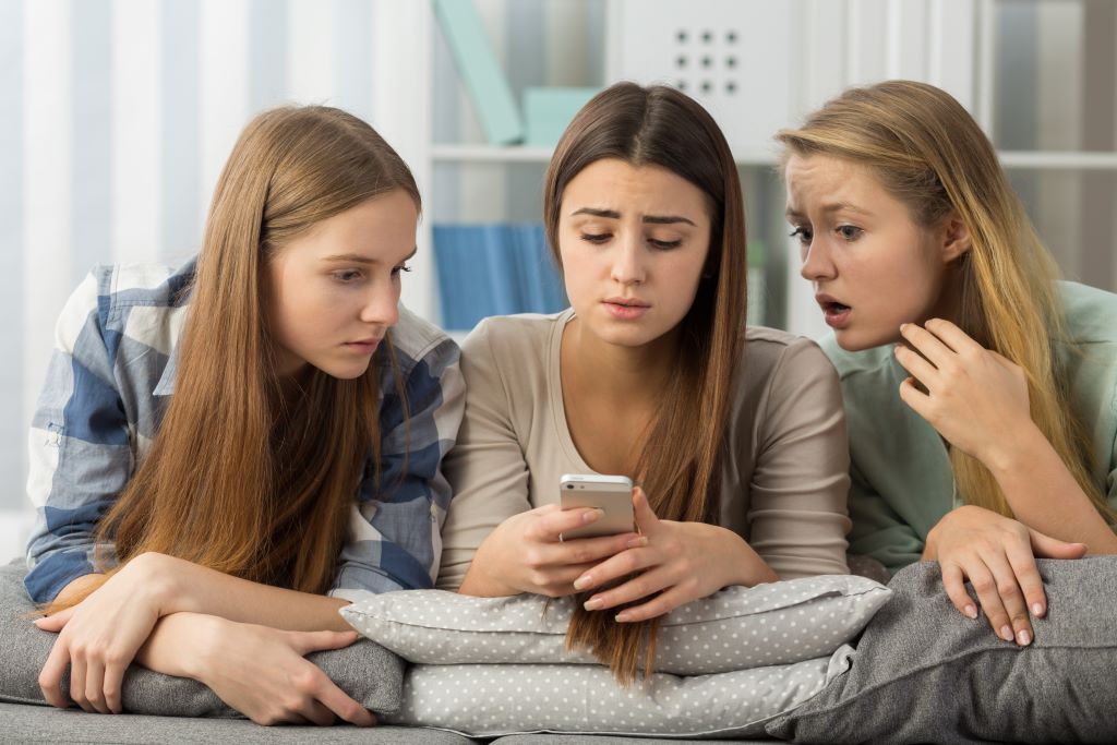 Three teenage girls looked concerned at a phone screen